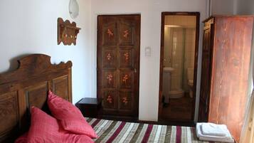 A bedroom with a wooden bed, a large wardrobe, and a door leading to a bathroom.