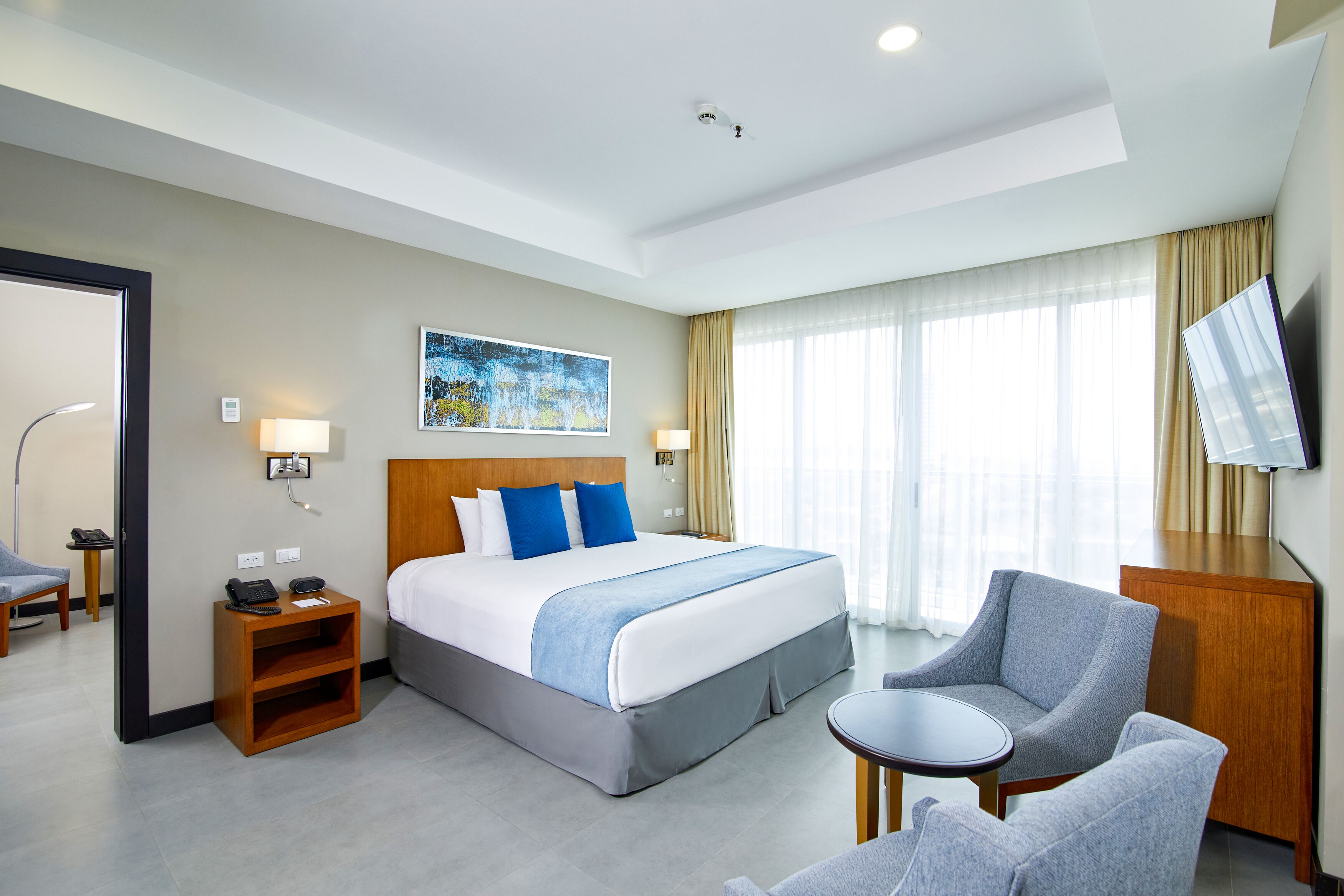 Une chambre d’hôtel avec un grand lit, un bureau, une chaise, une télévision et un tableau au mur.