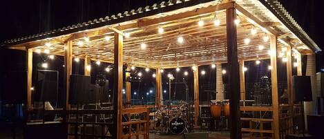 A covered outdoor stage with musical instruments and lighting.