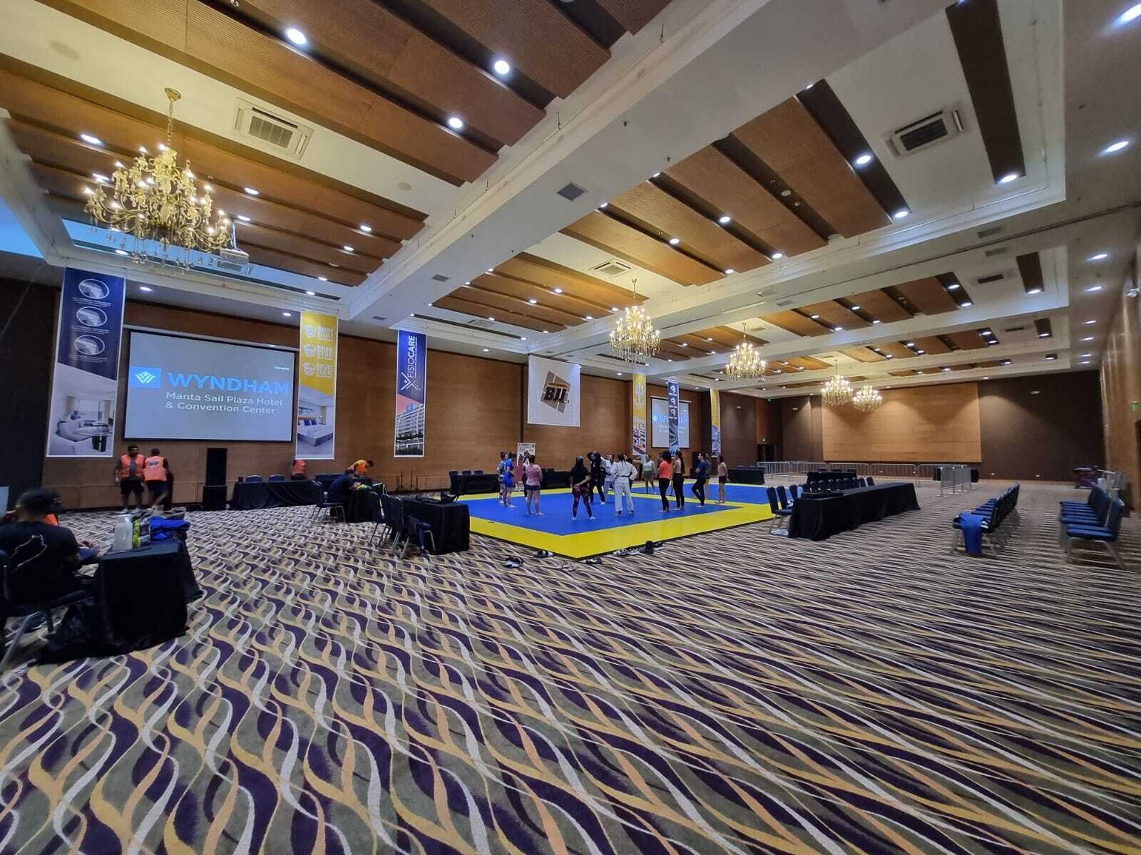 A large conference room with a stage, multiple rows of chairs, and banners on the walls.