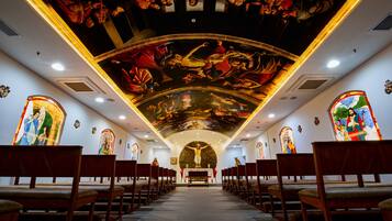 An interior of a church with wooden pews, a central altar, and stained glass windows.