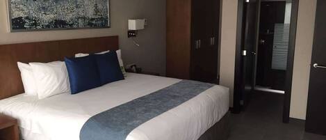 A hotel room with a large bed, a nightstand, a wardrobe, and a painting on the wall.