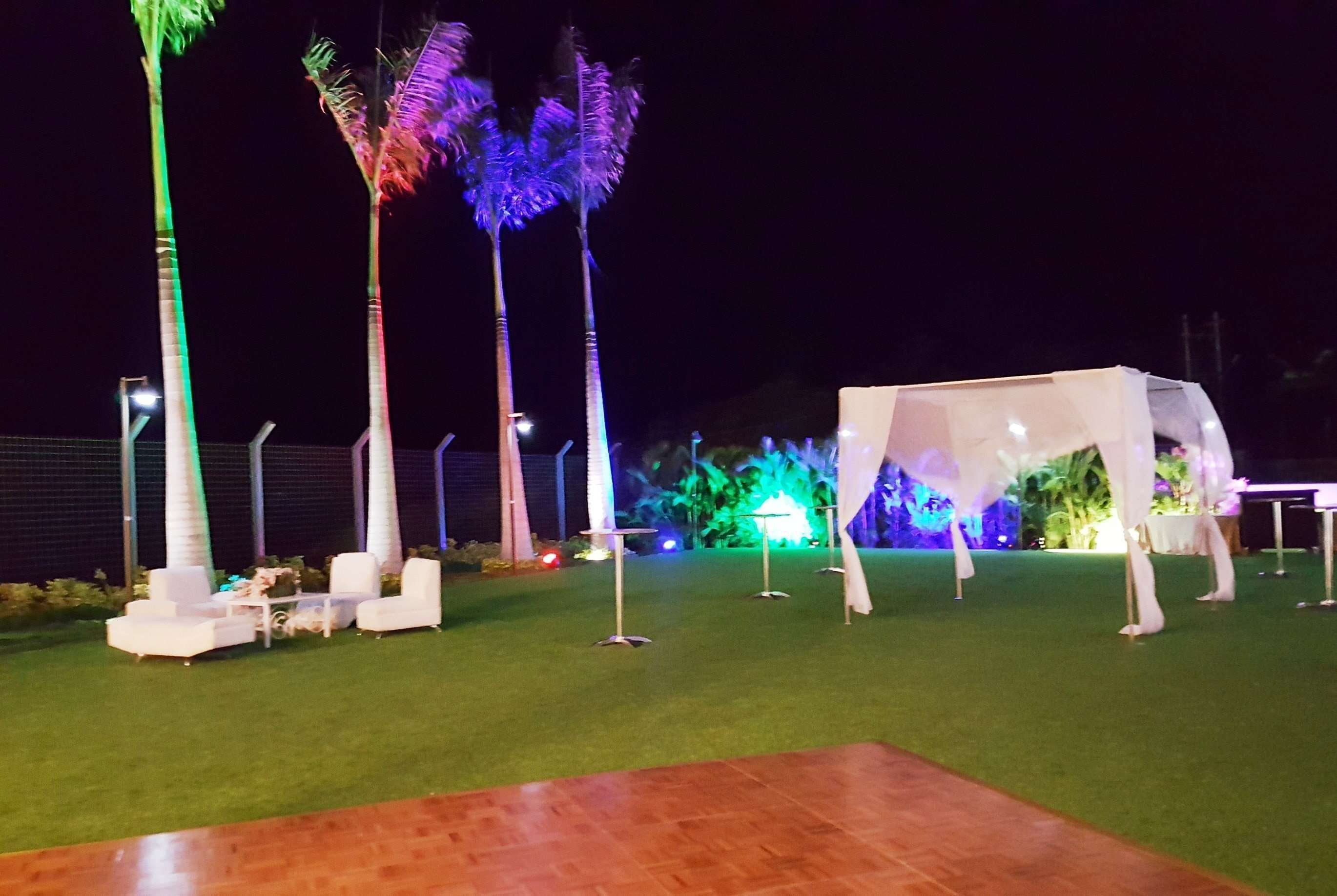 An outdoor area with artificial grass, white furniture, and palm trees.