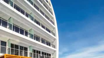 Um edifício moderno com piscina, apresentando um céu azul límpido e uma superfície de água calma.