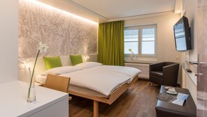 A hotel room with a bed, a desk, a chair, a TV, and a window with curtains. - Hotel Weiss Kreuz (Thusis)