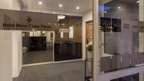 A hotel entrance with a sign for Hotel Weiss Kreuz Thuisis. - Hotel Weiss Kreuz (Thusis)