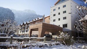 A hotel with a modern design, featuring a prominent entrance and a view of snow-covered mountains in the background. - Hotel Weiss Kreuz (Thusis)