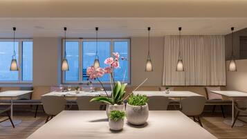 Un espace de restauration moderne, avec des tables, des chaises et des luminaires suspendus.