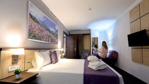 Une chambre d’hôtel avec un lit, un bureau, une chaise, une télévision et un tableau au mur.