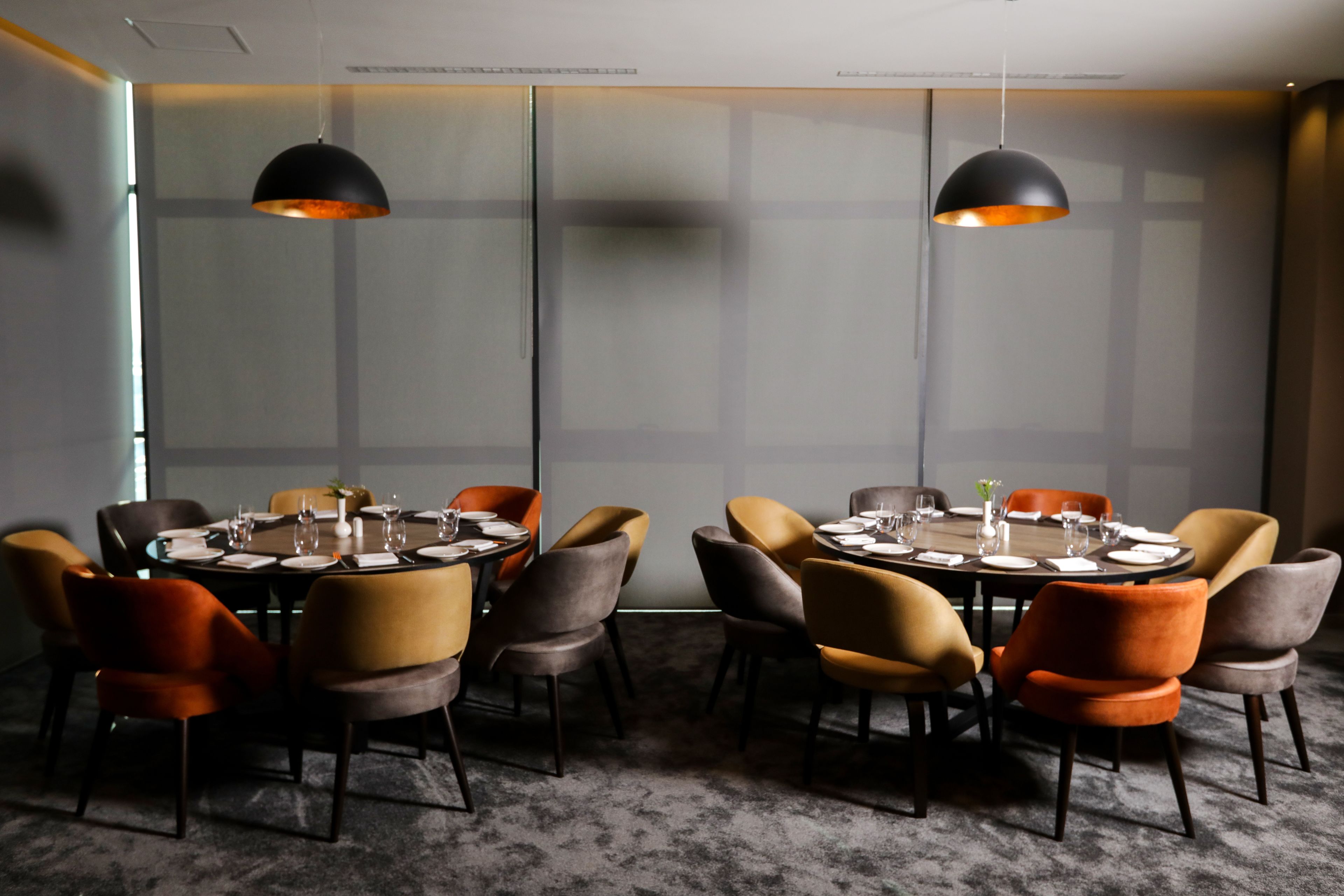 A conference room with round tables, chairs, and pendant lighting.