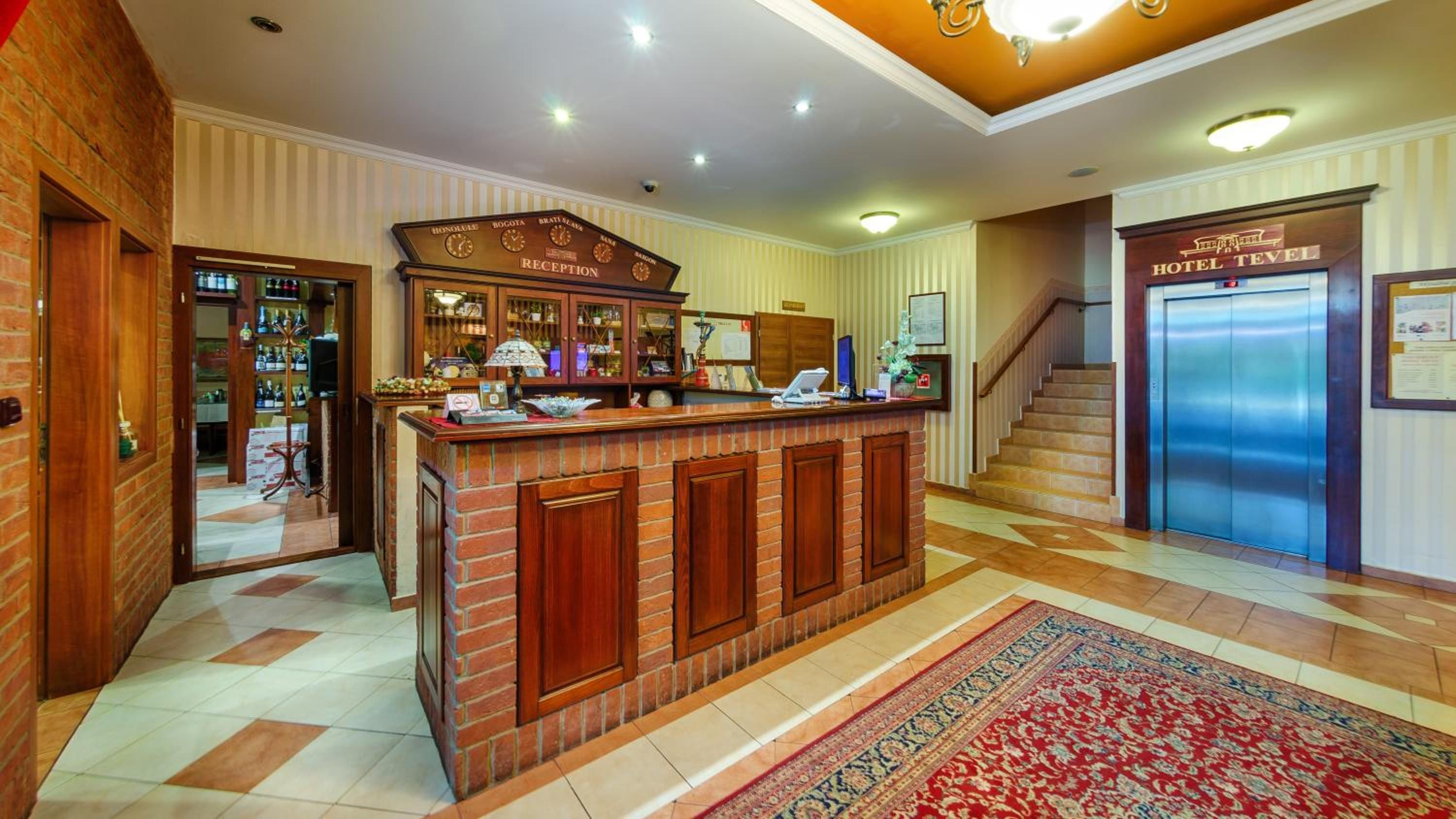 A reception area with a reception desk, a clock, and a staircase leading to an elevator.