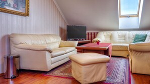 A living room with a sofa, ottoman, and a television.