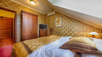 A bedroom with a bed, wardrobe, television, and a painting on the wall.