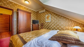 A bedroom with a bed, wardrobe, television, and a painting on the wall.