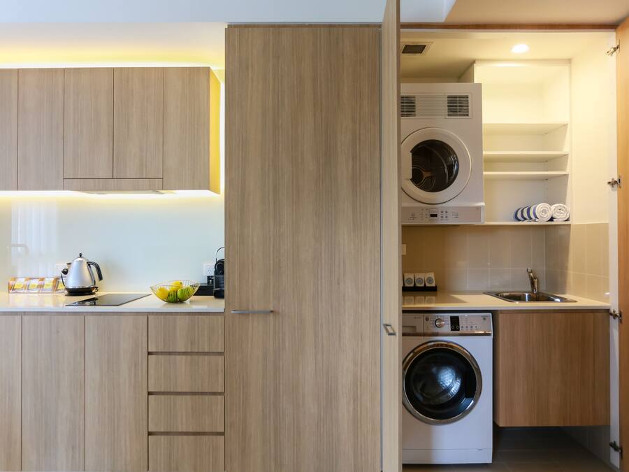 A compact kitchen with wooden cabinets, a built-in washing machine, and a sink.