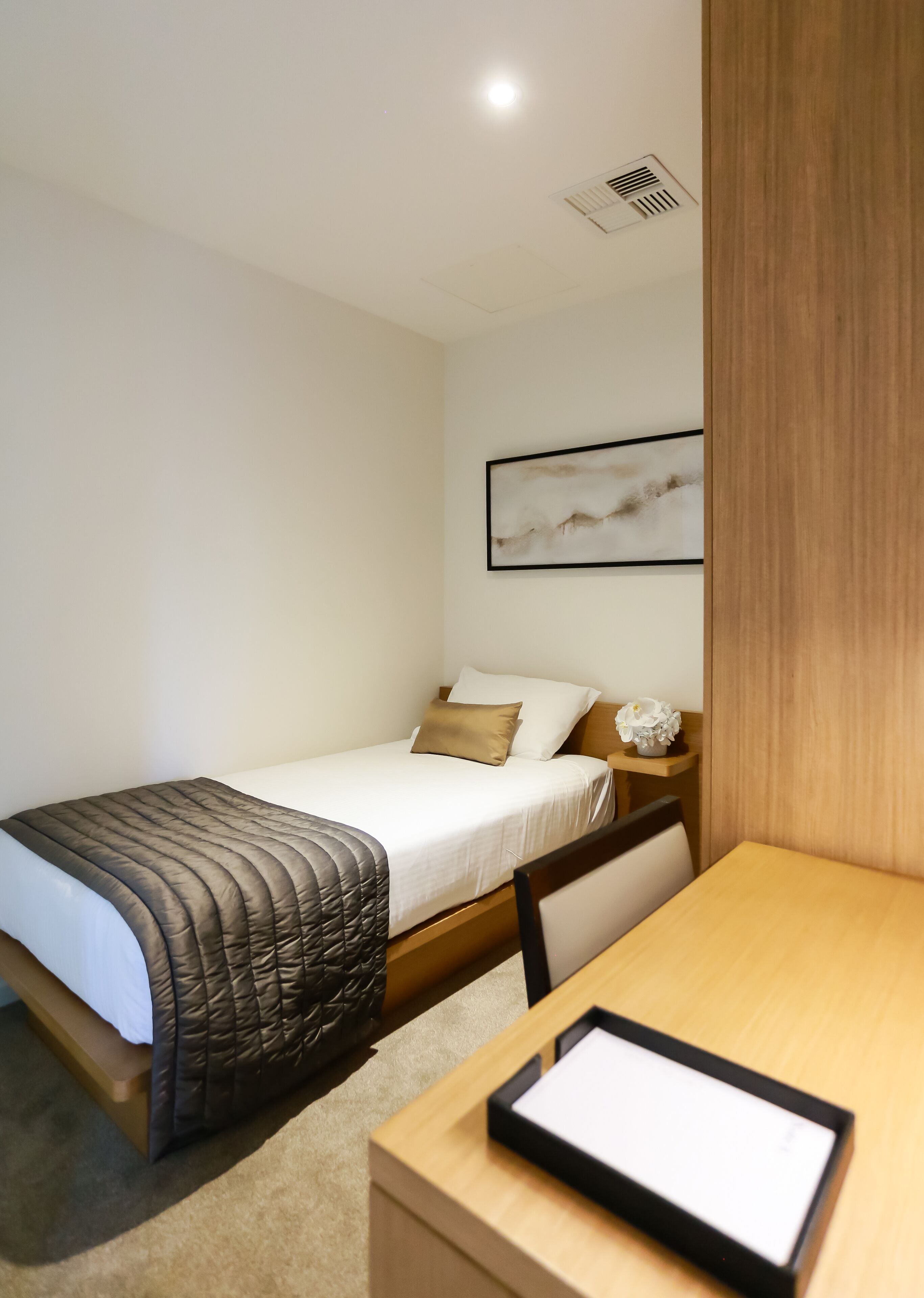 Une chambre à coucher avec un lit, une table de chevet et un tableau encadré accroché au mur.