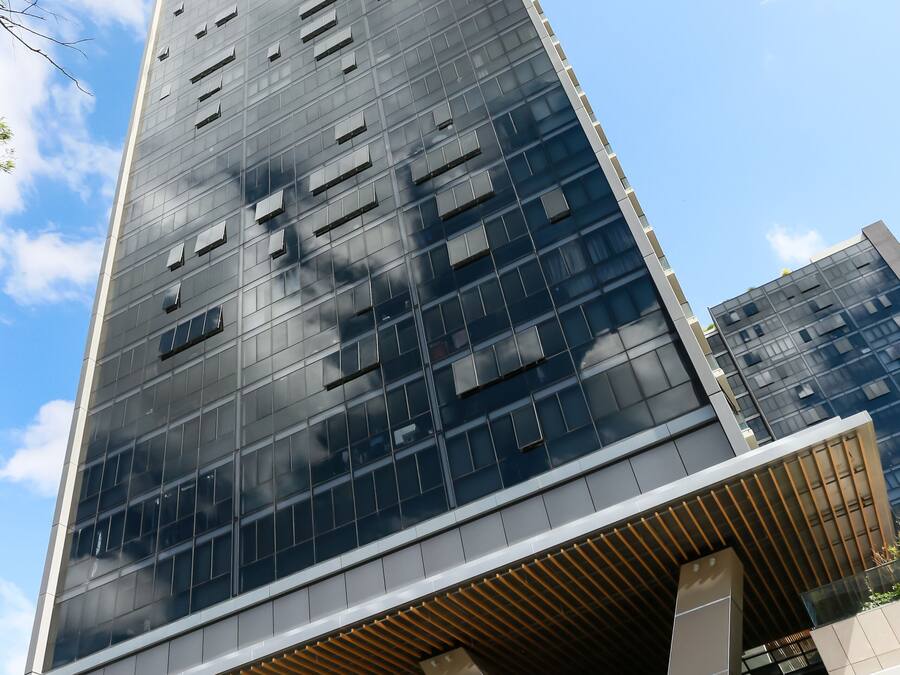 A modern high-rise building with a glass facade and a unique wooden slatted structure at the base.