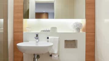 A modern bathroom with a white sink, toilet, and a large mirror.