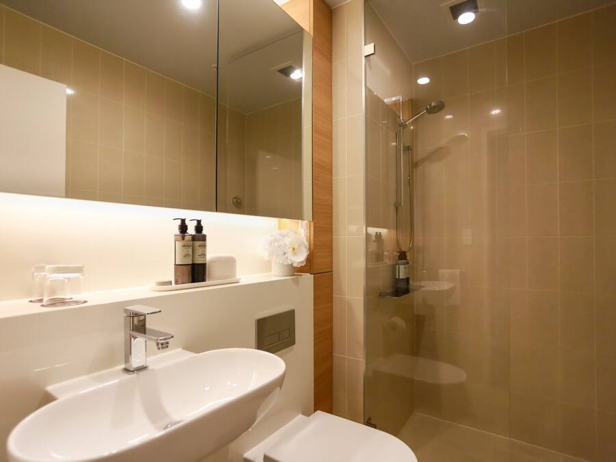 Une salle de bain moderne avec un grand miroir, un lavabo et un espace douche.