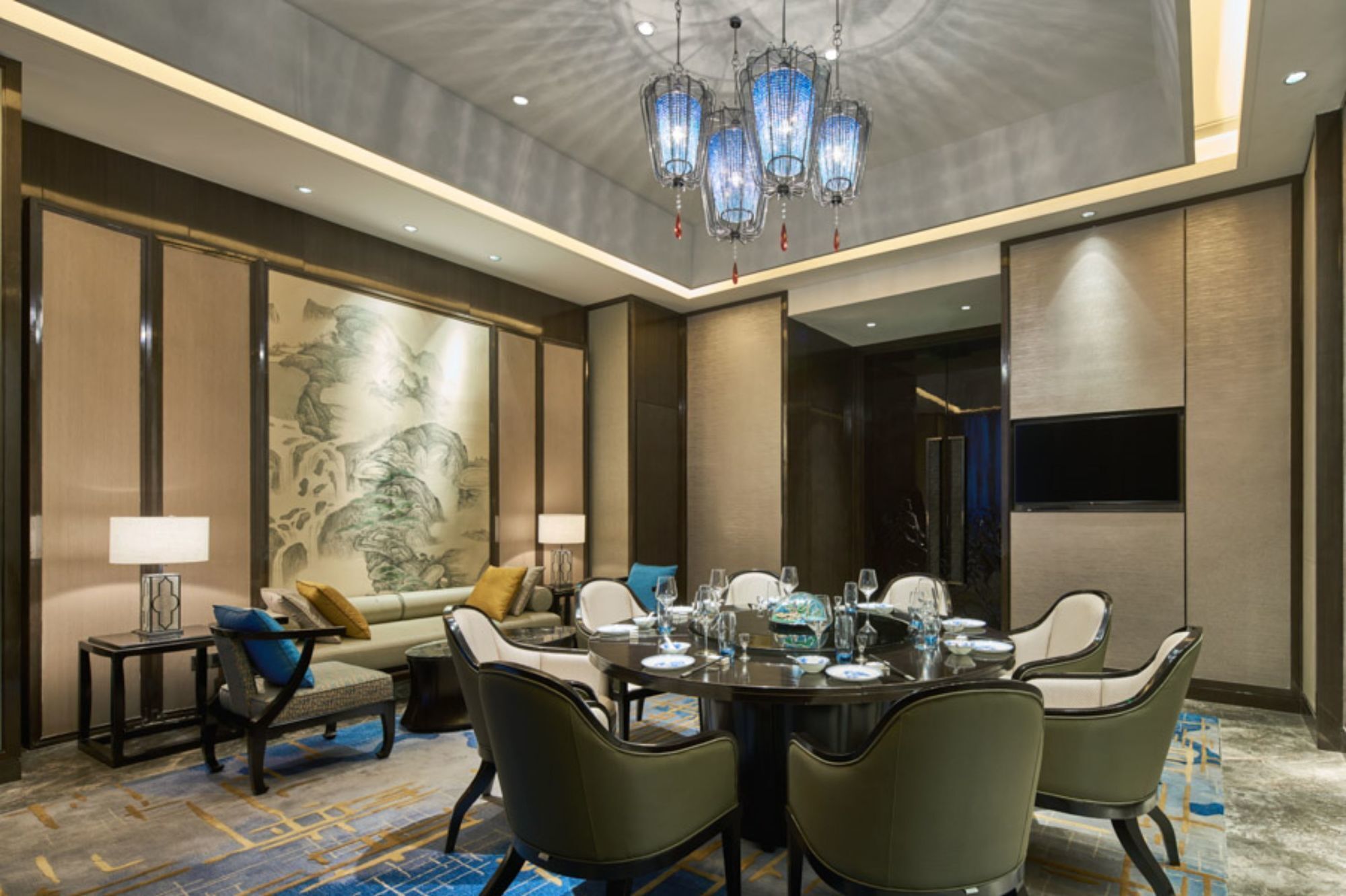 A dining area with a round table set for six, surrounded by upholstered chairs.