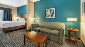 Una habitación de hotel con una cama, un sofá, una mesita de café y dos lámparas.