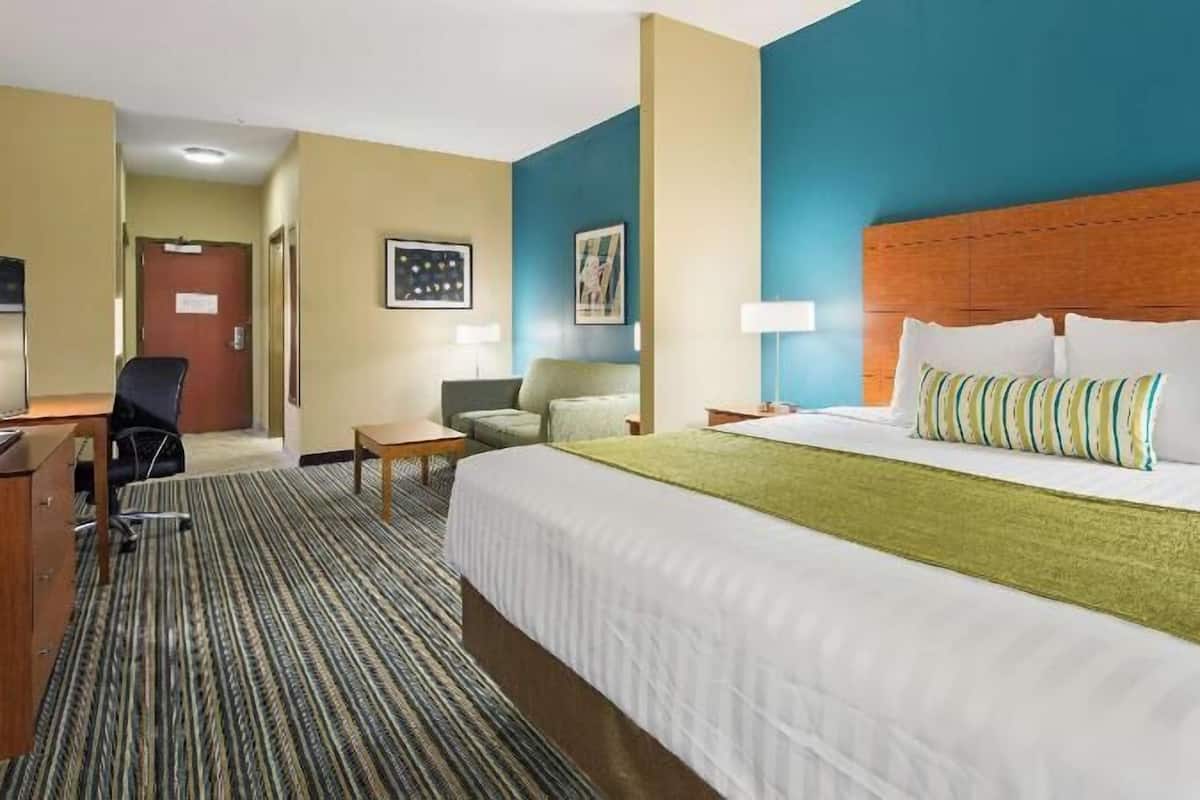 Ein Hotelzimmer mit einem großen Bett, einem Schreibtisch, einem Stuhl und einem kleinen Tisch.
