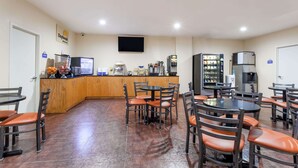 A dining area with multiple tables and chairs, a kitchen counter with appliances, and a vending machine.