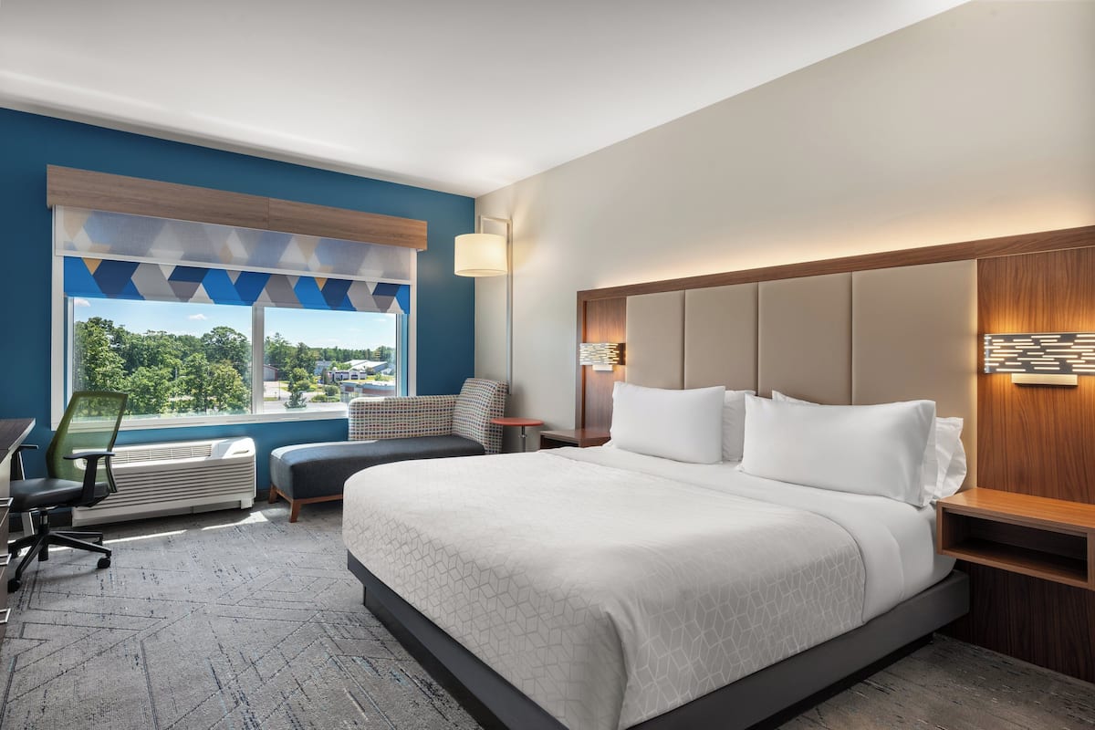 Une chambre d’hôtel avec un grand lit, un bureau et une vue sur l’extérieur.