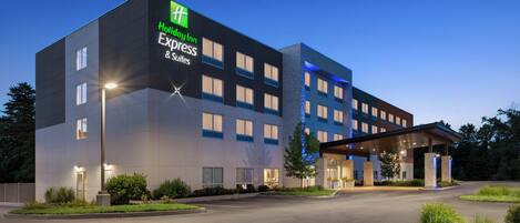 Un edificio de Holiday Inn Express con diseño moderno, que presenta una entrada amplia y un área de estacionamiento techada.