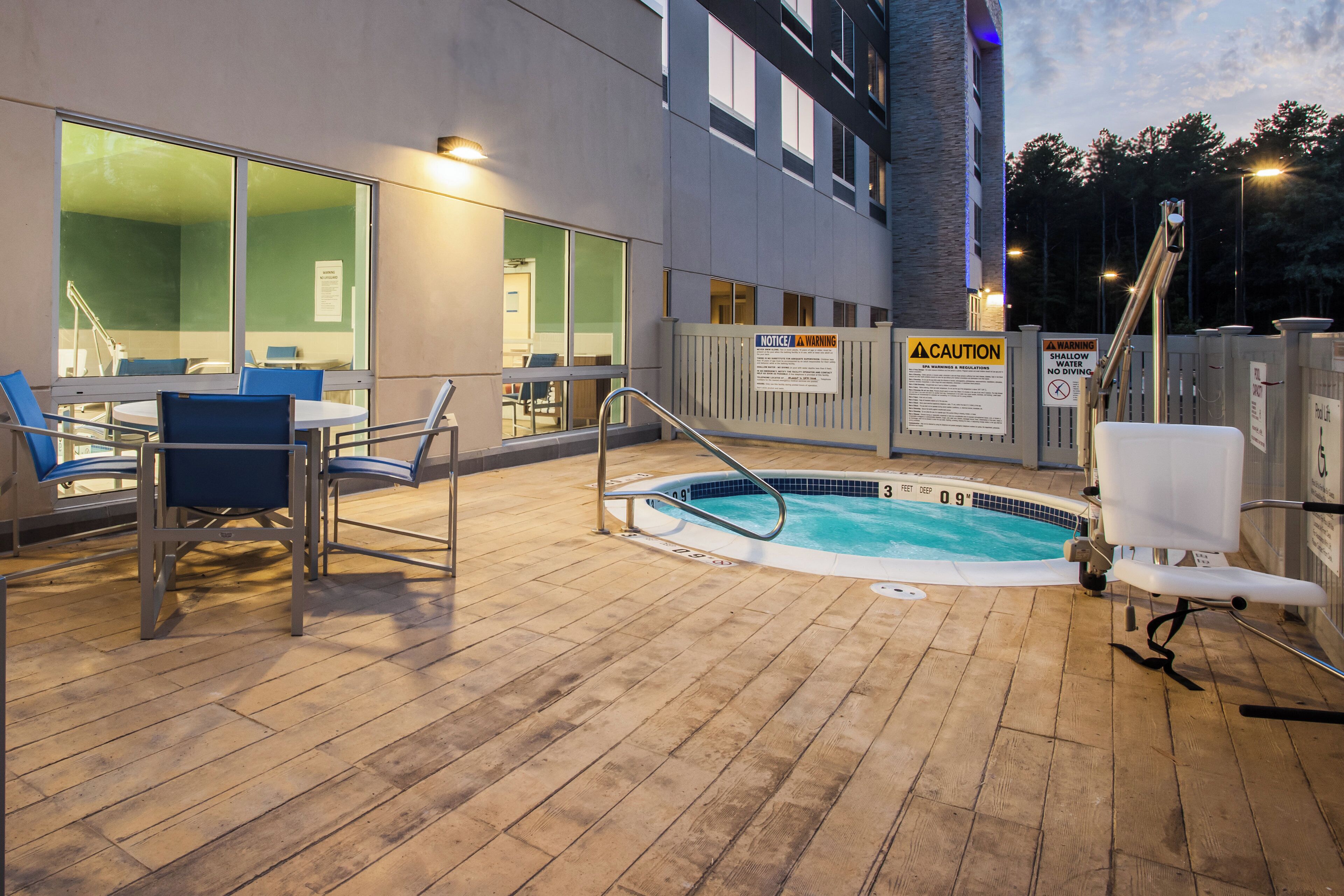 An outdoor pool area with a wooden deck, lounge chairs, and a pool ladder.