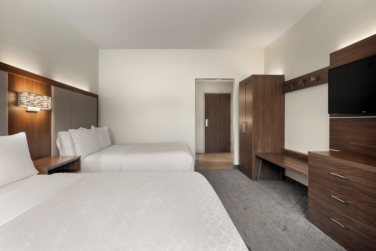 Une chambre d’hôtel avec deux lits, une télévision, une armoire et un petit bureau.
