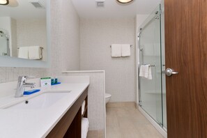 Une salle de bain moderne avec un lavabo blanc, un miroir et une douche en verre.