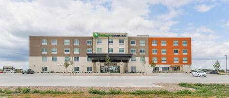 A multi-story Holiday Inn Express & Suites hotel with a parking lot in front.
