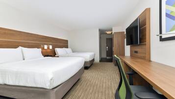 A hotel room with two beds, a desk, a chair, a TV, and a door leading to a bathroom.