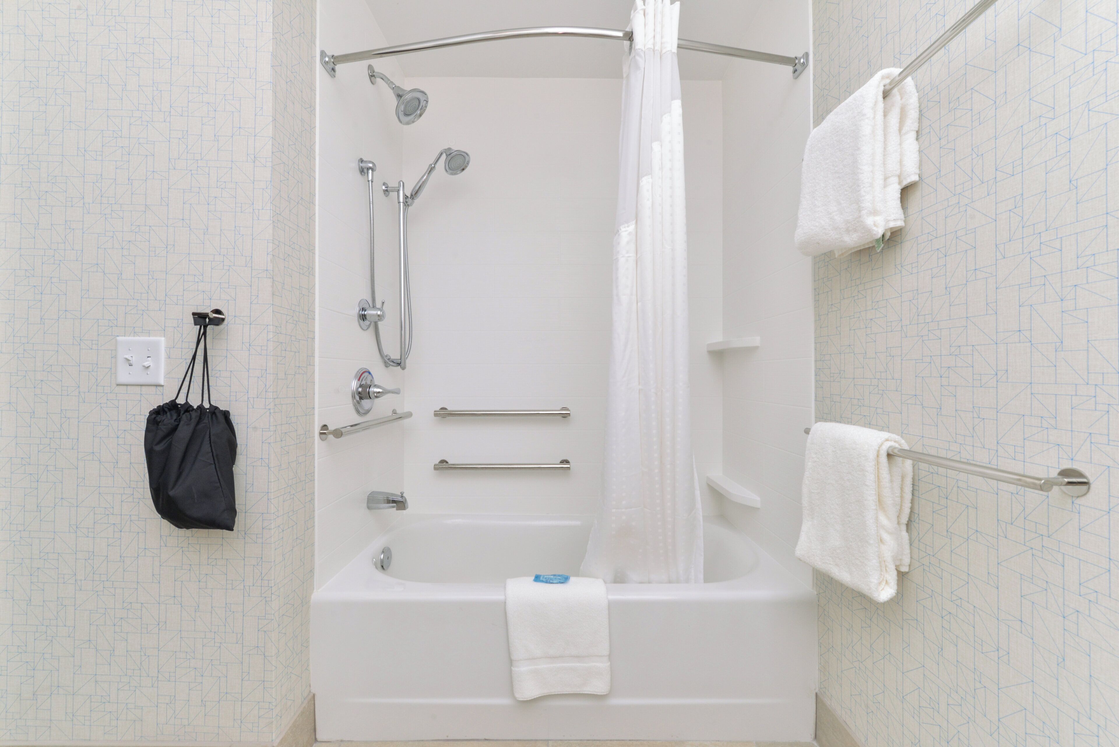 A modern bathroom with a walk-in shower, grab bar, and a towel rack.