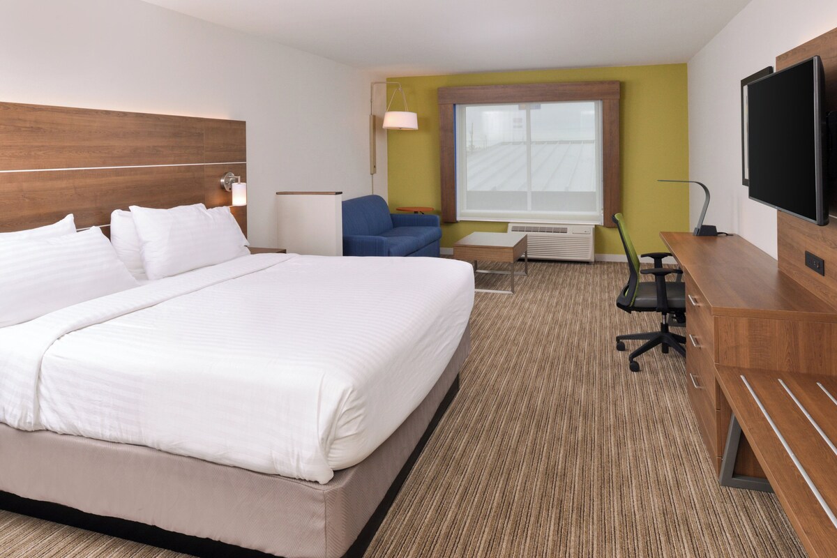 Une chambre d’hôtel avec un grand lit, un bureau, une chaise, une télévision et une fenêtre.