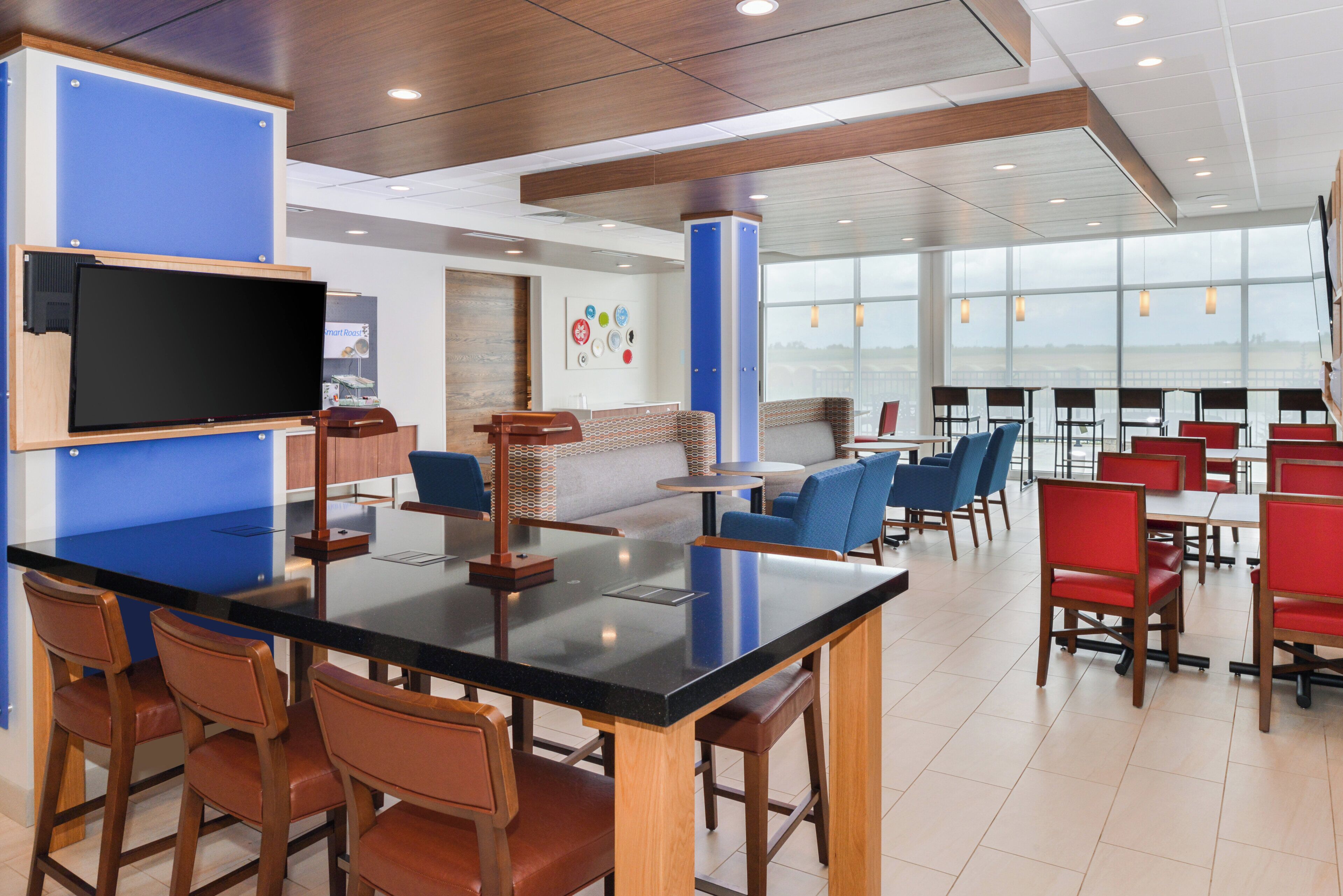 A modern restaurant with a black bar, wooden chairs, and a blue accent wall.