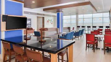 A modern restaurant with a black bar, wooden chairs, and a blue accent wall.