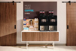 Un espace dédié au café, comprenant deux machines à café, une cafetière à piston et divers accessoires liés au café, le tout disposé sur un comptoir en bois.