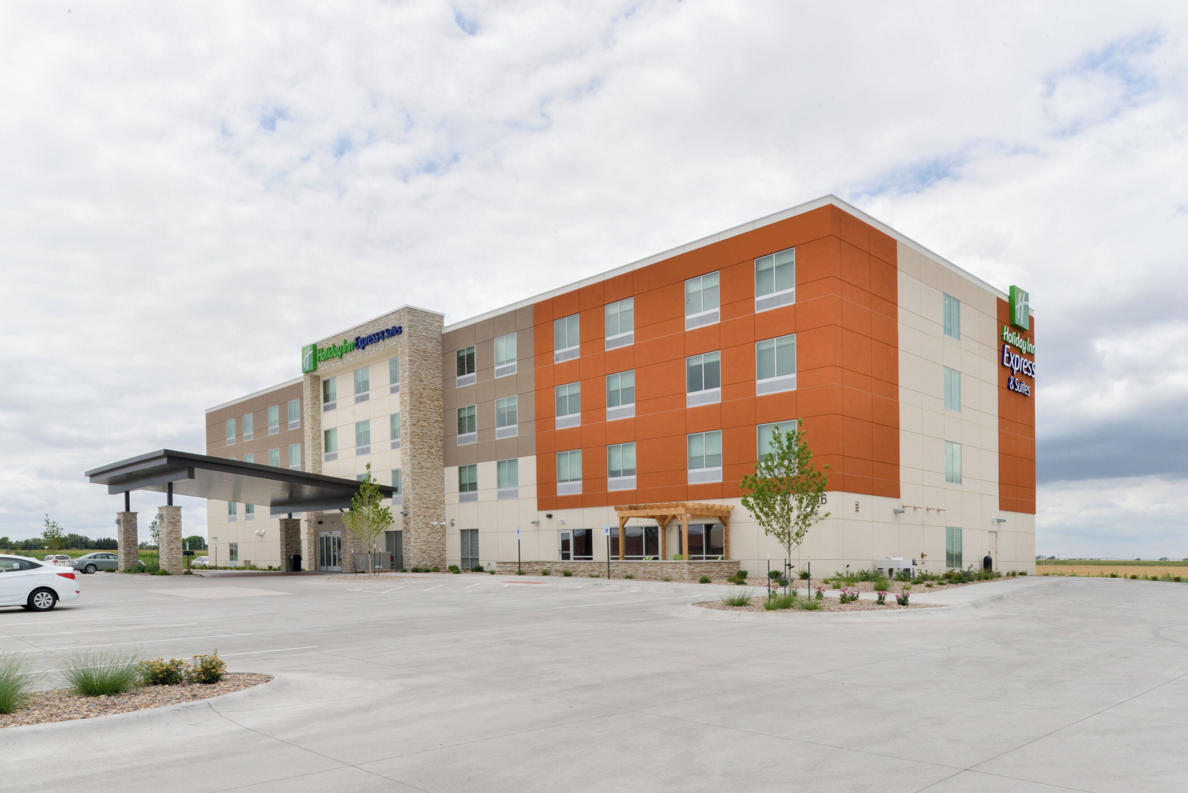 A Holiday Inn Express & Suites hotel with a modern design, featuring a stone facade and a covered entrance.