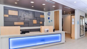 A hotel reception desk with a modern design, a clock, and a sign indicating check-in and check-out times. - Holiday Inn Express & Suites Ogallala by IHG (Ogallala)
