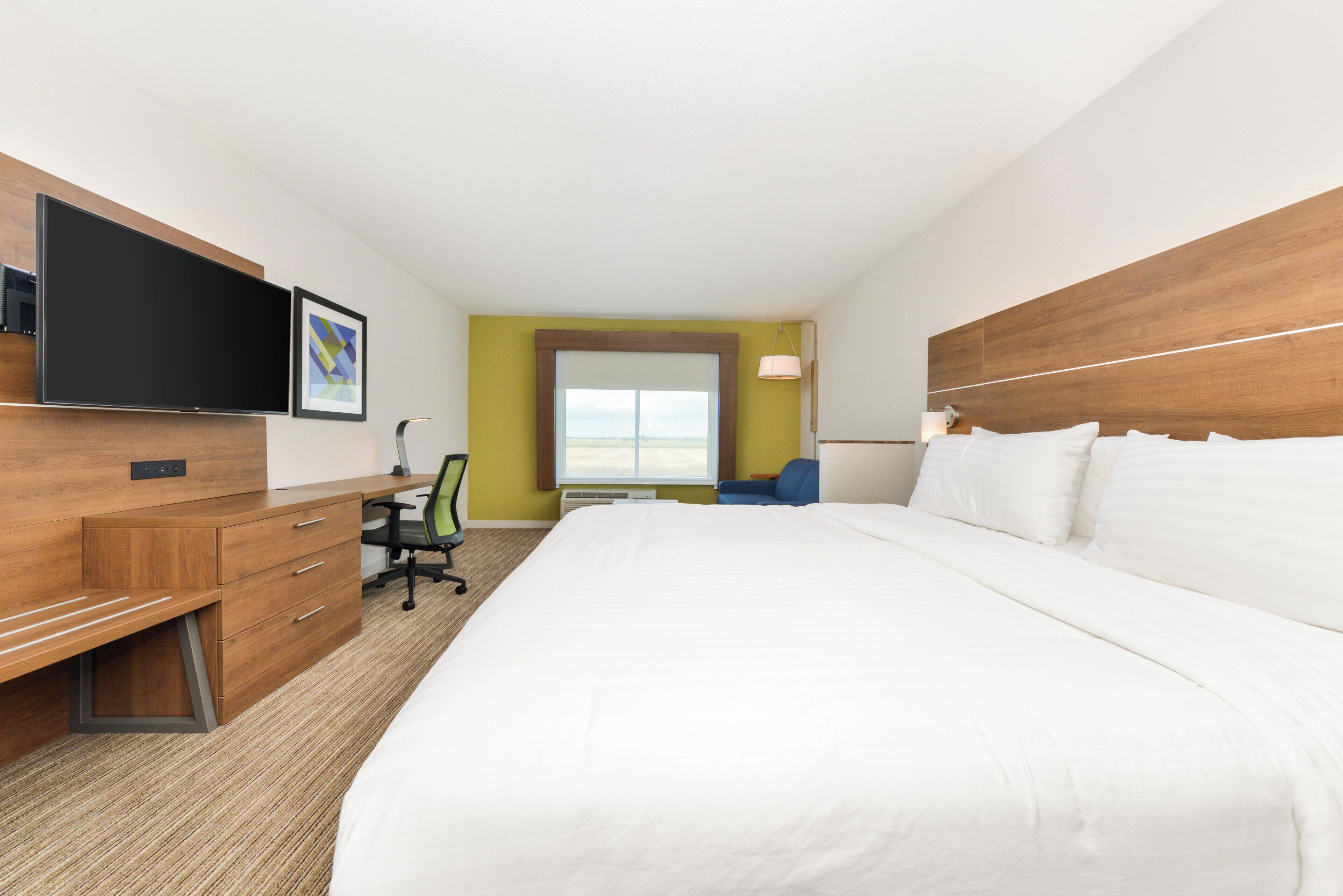 Una habitación de hotel con una cama grande, un escritorio, una silla, un televisor y una ventana.