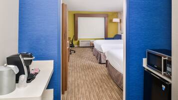A hotel room with a bed, a desk with a coffee maker, a TV, and a microwave.