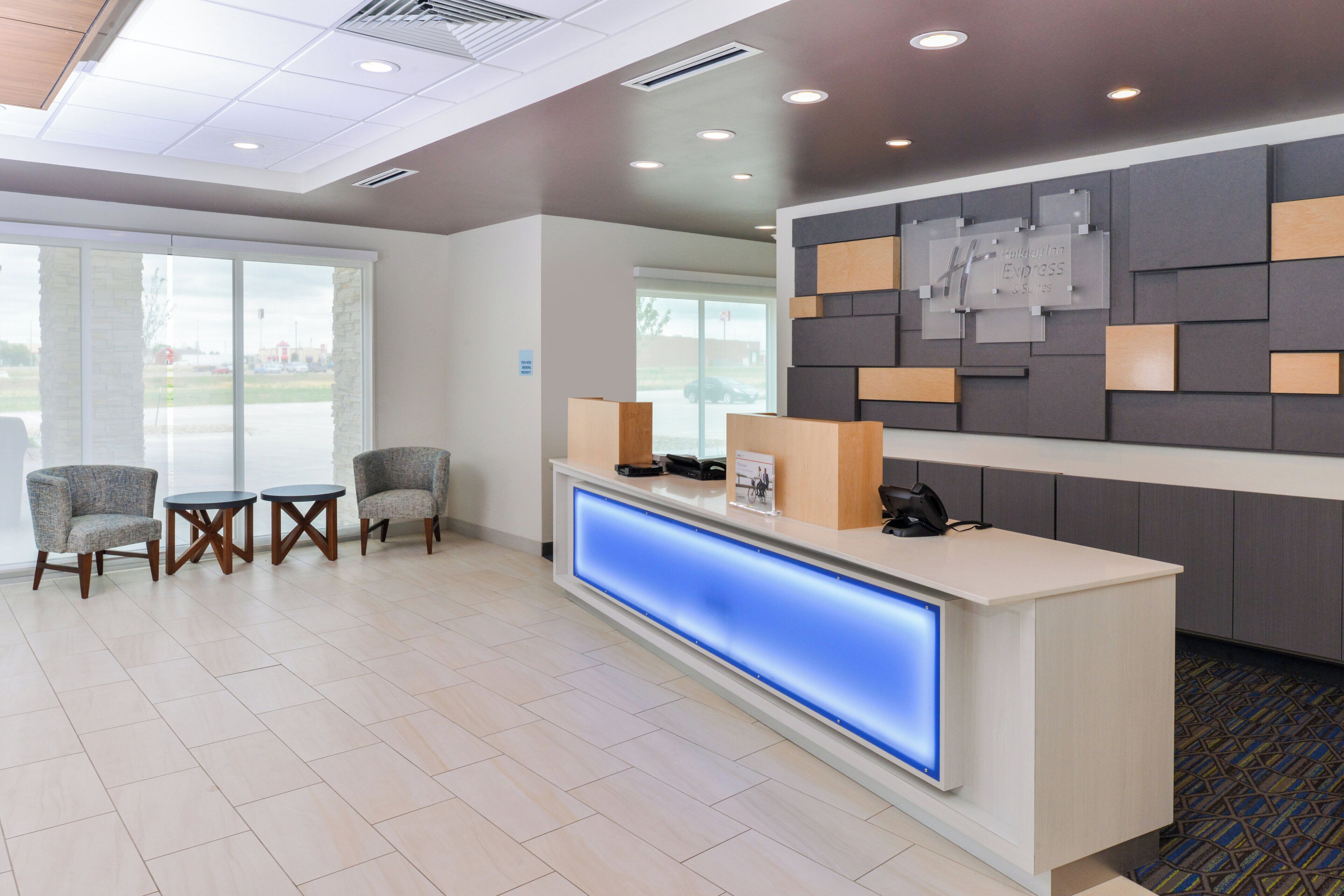 A hotel reception area with a reception desk, seating area, and a view of the outside.