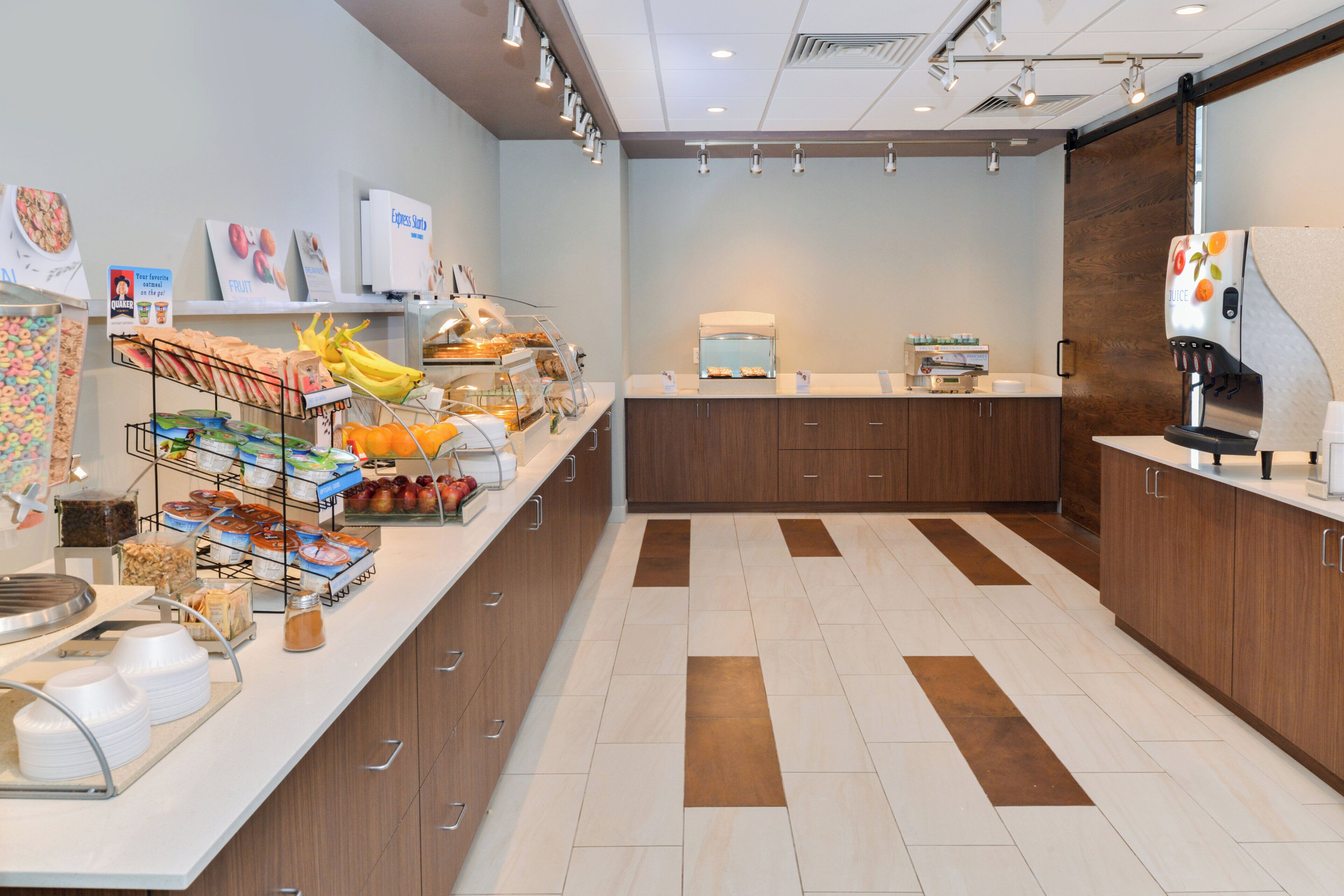 A breakfast bar with various food items and a juice dispenser.