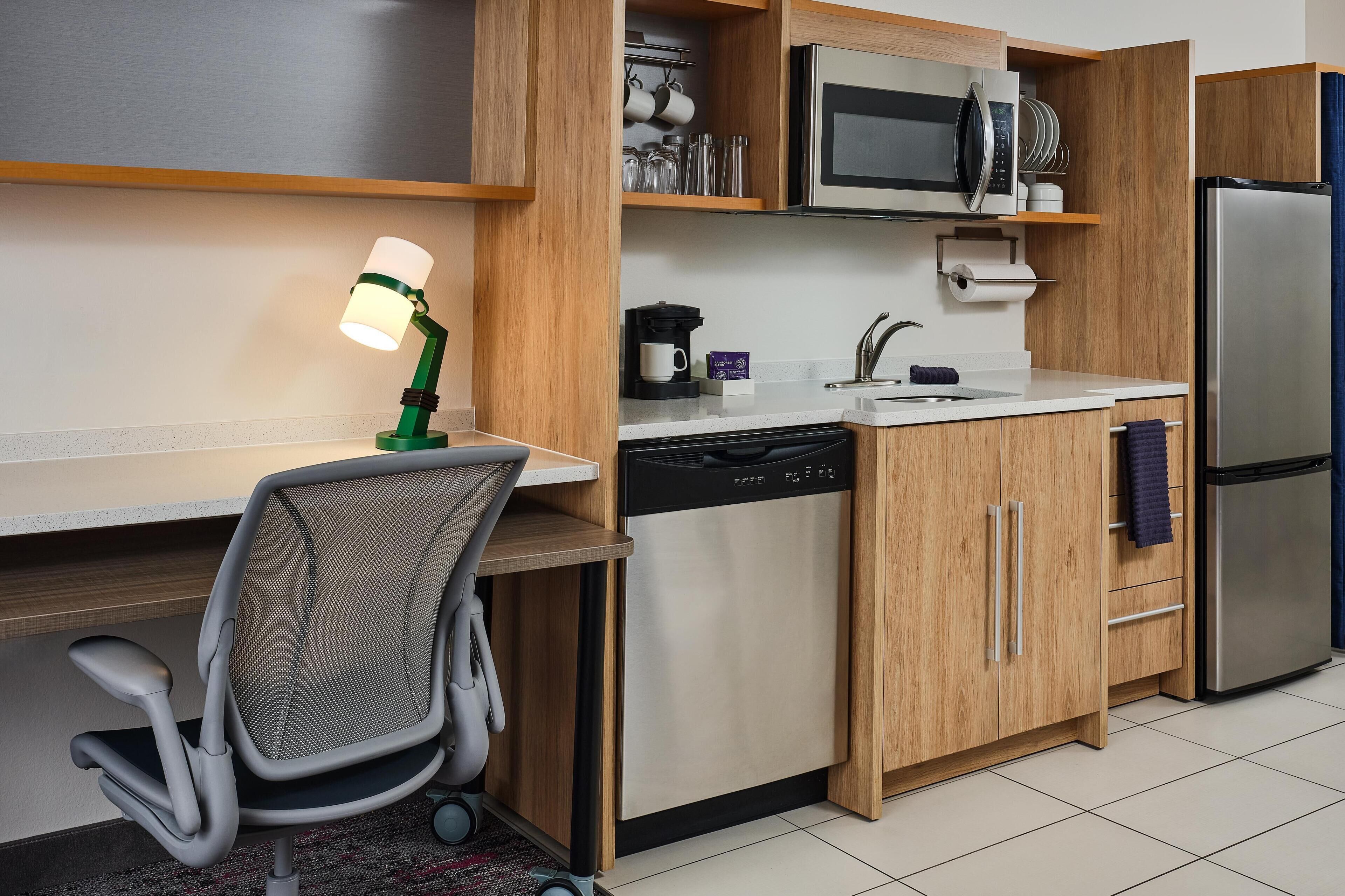 Cocina compacta equipada con microondas, cafetera, lavavajillas y refrigerador.