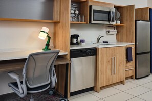 Cocina compacta equipada con microondas, cafetera, lavavajillas y refrigerador.