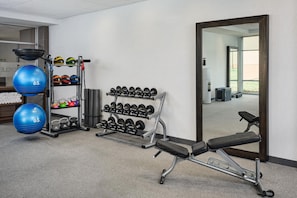 A gym with exercise equipment, a bench, and a mirror. - Home2 Suites by Hilton Rapid City (Rapid City)