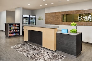A hotel reception area with a counter, a minibar, and a wall-mounted sign.