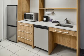 A modern kitchen with a stainless steel refrigerator, a microwave, a coffee maker, and a sink. - Home2 Suites by Hilton Rapid City (Rapid City)